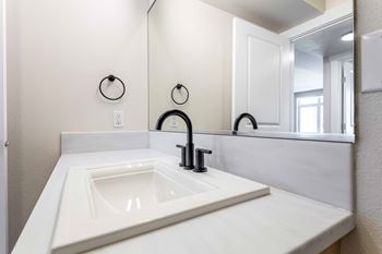 Bathroom vanity with black fixtures and mirror